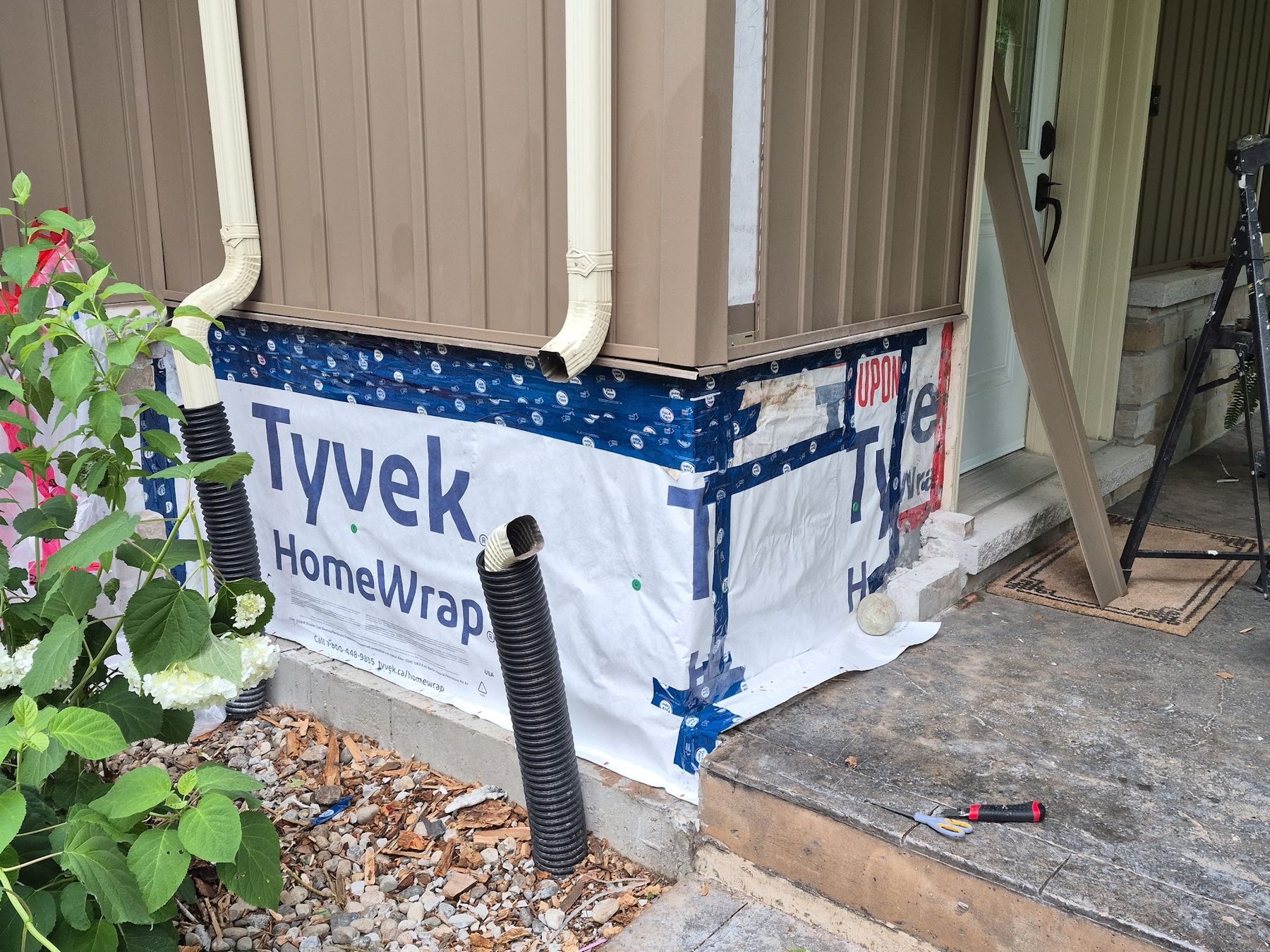 House corner with the stone veneer removed and house wrap exposed